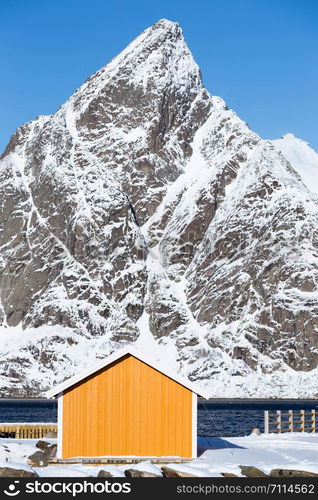 traditional norwegian wooden house rorbu to stand on the shore of the fjord and mountains in the distance. Lofoten Islands. Norway. world travel