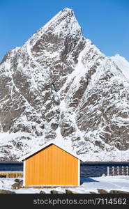 traditional norwegian wooden house rorbu to stand on the shore of the fjord and mountains in the distance. Lofoten Islands. Norway. world travel