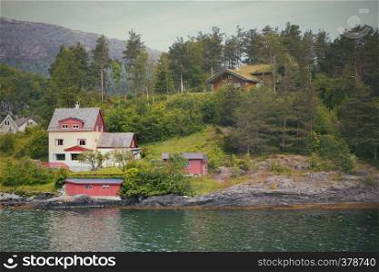 traditional norwegian wooden house to stand at the lakeside and mountains in the distance, norway