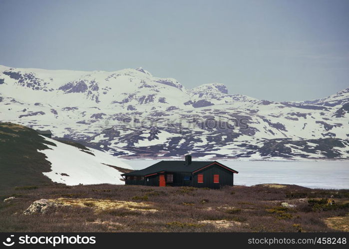 traditional norwegian wooden house to stand at the lakeside and mountains in the distance, norway