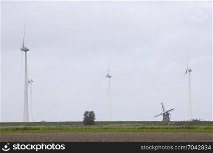traditional old dutch windmill goliath and wind turbines near eemshaven in the northern province groningen of the netherlands and blue sky