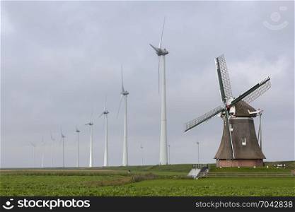 traditional old dutch windmill goliath and wind turbines near eemshaven in the northern province groningen of the netherlands and blue sky
