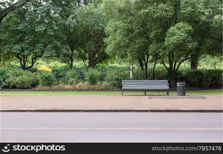 Traditional Park Bench with Litter Trash Bin in Green park with Pavement Sidewalk