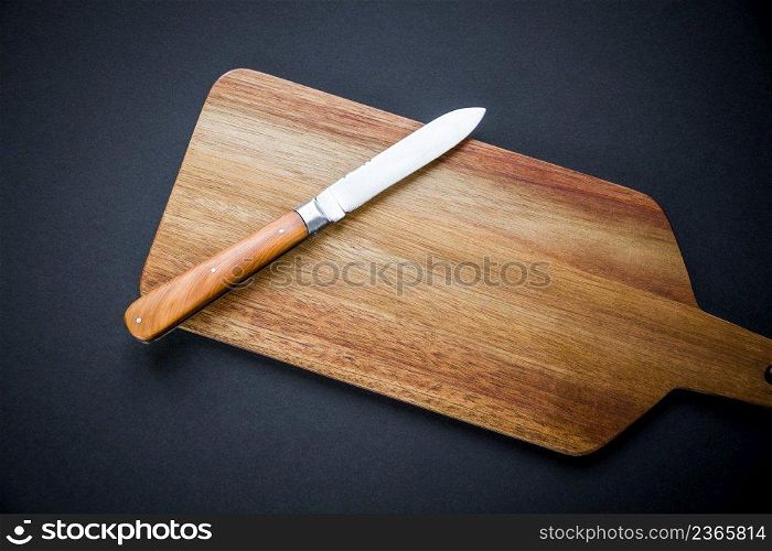 Traditional pocket knife on a wooden cutting board. Black background. Traditional pocket knife on a wooden cutting board
