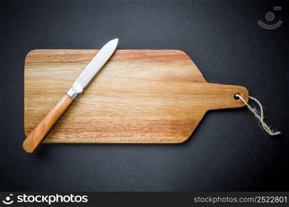Traditional pocket knife on a wooden cutting board. Black background. Traditional pocket knife on a wooden cutting board