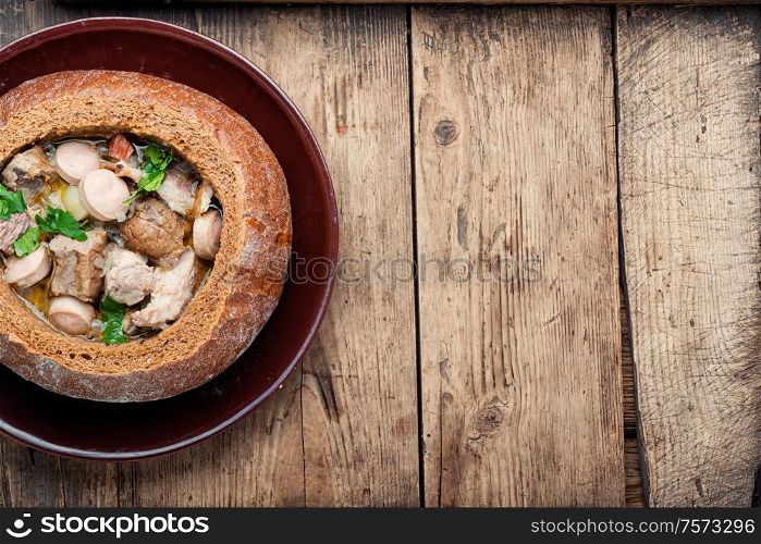 Traditional polish flour soup or zurek soup on wooden table.Polish cuisine.Space for text. Polish soup zurek in bread pot