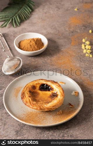 Traditional Portuguese pastry Pastel de Nata or Pastel de Belem served with cinnamon powder in a traditional tray on a rustic board. Egg tart