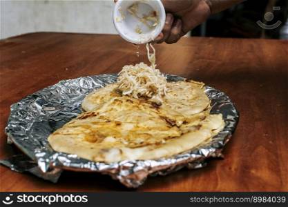 Traditional pupusas served with salad on the table. Nicaraguan pupusas with salad on aluminum foil, View of delicious Salvadoran pupusas served on wooden table.