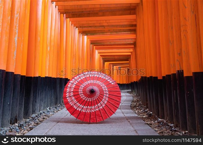 Traditional red Japanese umbrella in Fushimi Inari Taisha in travel holidays vacation trip outdoors concept in Kyoto, Japan. Red poles in the temple. Walkway tunnel of shrine.