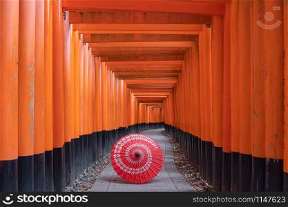 Traditional red Japanese umbrella in Fushimi Inari Taisha in travel holidays vacation trip outdoors concept in Kyoto, Japan. Red poles in the temple. Walkway tunnel of shrine.