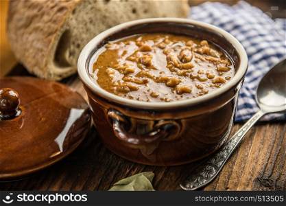 traditional rural tripe soup in brown ceramic dish with bread in the background