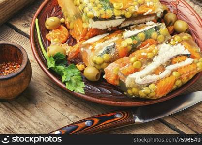 Traditional Russian dish fish.Jellied fish in a plate on a wooden background.Fish food.. Appetizing jellied fish.