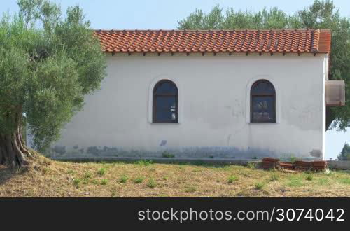 Traditional small house between green trees in sunny day in Greece