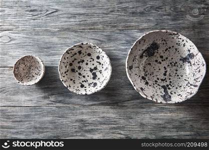 Traditional souvenir ceramic handcrafted plates and bowls on a concrete background with place under text. Flat lay.. Ceramic bowls of different sizes are empty on a gray wooden background. Flat lay of porcelain dishes handmade.