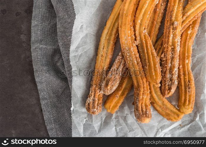 Traditional Spanish and Mexican dessert churros on black stone background.