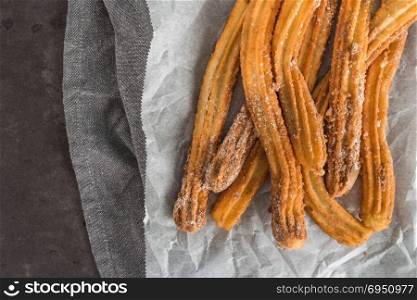 Traditional Spanish and Mexican dessert churros on black stone background.