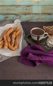 Traditional Spanish and Mexican dessert churros with hot chocolate sauce on black stone background.