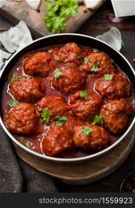 Traditional spicy meatballs in tomato sauce with pepper, garlic and parsley on black. Macro