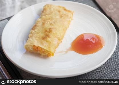 Traditional spring rolls fried and sweet chili sauce on white plate at restaurant.