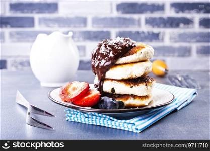 Traditional syrniki served with fresh strawberries, blueberry, m∫≤aves, drizz≤d with chocolate