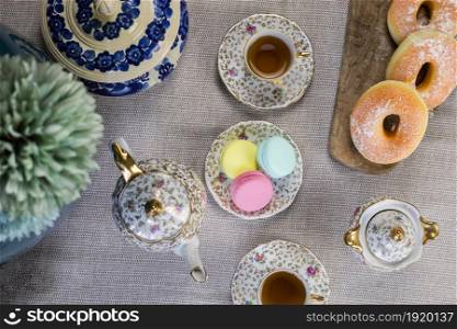 Traditional table with cup of tea and tea pot and colorful macaron lovely cozy table at home,Mother&rsquo;s Day tea setting with teapot, close up. Traditional table with cup of tea and tea pot and colorful macaron lovely cozy table at home,Mother&rsquo;s Day tea setting with teapot,