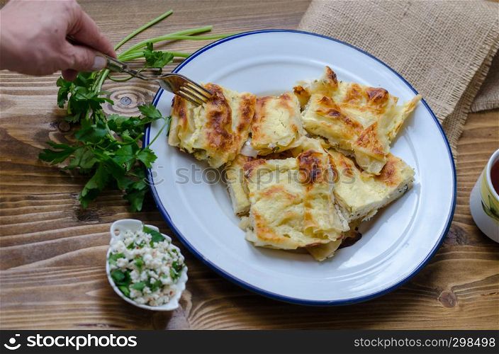 Traditional turkish borek in a enamel dish on wooden table.
