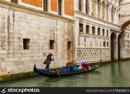 Traditional Venice gondola ride under the Bridge of Sighs on the channel in rainy weather, Italy