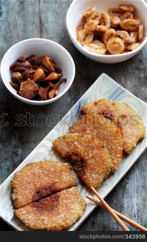 Traditional Vietnamese food on tet, sliced of glutinous rice cake fried on plate with pickled on plate, photo from top view on wooden background