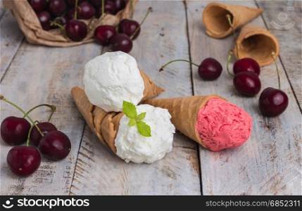 Traditional waffle cones for ice cream on wooden table. Cherry ice cream and fresh cherries. Cones filled with ice cream