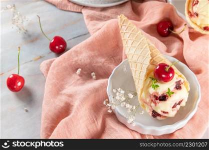 Traditional waffle cones with ice cream and cherry fruits on marble stone surface