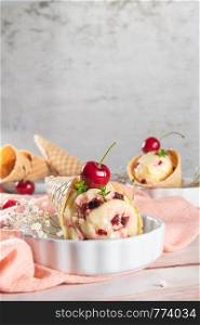 Traditional waffle cones with ice cream and cherry fruits on marble stone surface.