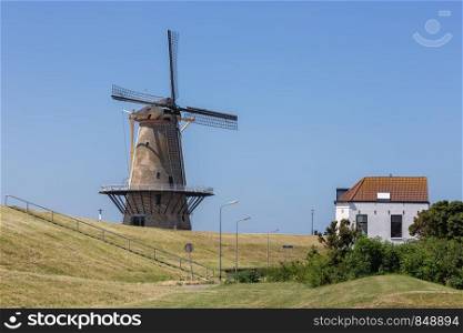 Traditional windmill at dike near Vlissingen, The Netherlands. Dutch traditional windmill at dike near Vlissingen