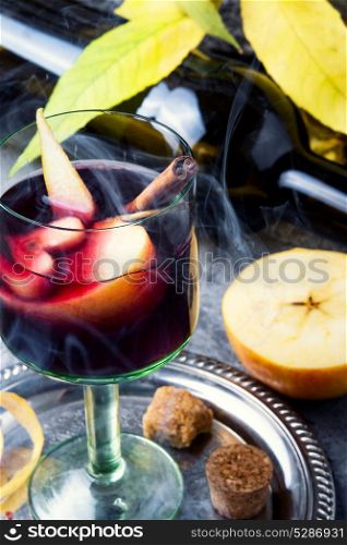 Traditional winter alcohol drink. Glass with red hot wine with apple and spices