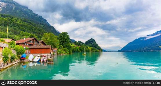 Traditional wood houses, boats and yacht on the Lake Brienz in swiss village Iseltwald, Switzerland. Swiss village Iseltwald, Switzerland