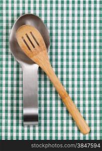 Traditional wooden spoon in stainless steel spoon rest on striped cloth napkin. Format in vertical layout.