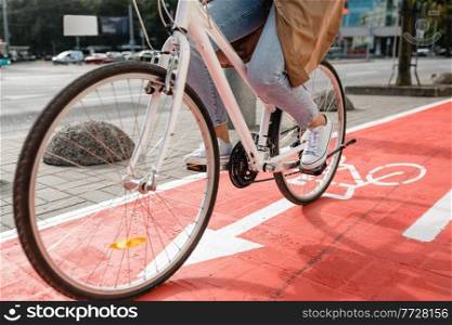 traffic, city transport and people concept - close up of woman cycling along red bike lane with signs of bicycles and two way arrows on street. woman cycling along red bike lane road in city