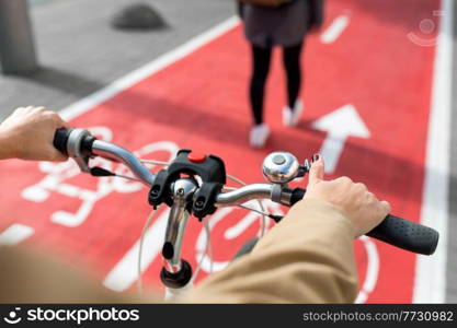 traffic, city transport and people concept - close up of woman cycling behind pedestrian walking along red bike lane on street in tallinn, estonia. close up of cyclist behind pedestrian on bike lane
