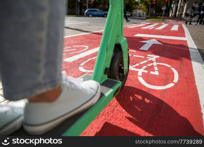 traffic, city transport and people concept - close up of woman riding electric scooter along red bike lane with signs of bicycles and two way arrows on street. woman riding scooter along bike lane road in city