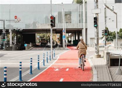 traffic, city transport and people concept - woman cycling along red bike lane with signs of bicycles and two way arrows on street in tallinn, estonia. woman cycling along red bike lane road in city