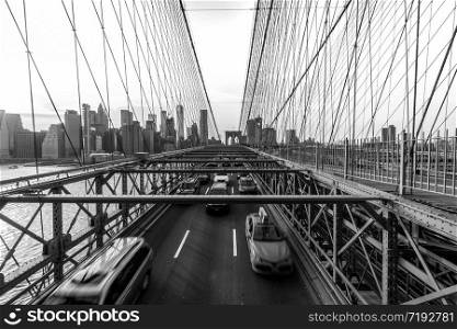 Traffic in rush hour after working day on the Brooklyn bridge over New York cityscape background with sunset, USA, United States, Business and transportation concept