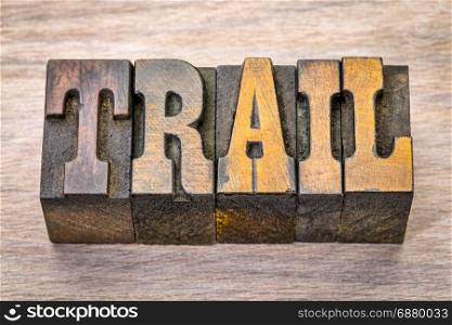 trail word in vintage letterpress wood type against grained wood
