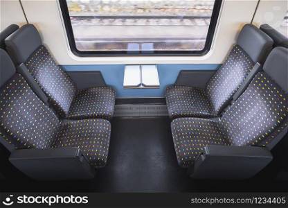 Train chairs inside swiss border train with railway tracks view on window. Train interior. Comfortable public transport. Eco-friendly transportation.
