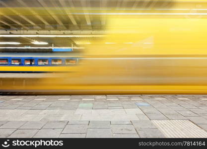 Train departing from a platform, leaving a blur and a glimpse on a waiting train on another platform