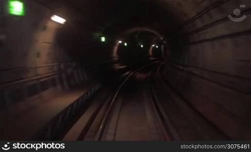Train moving along curved rail track in dark underground tunnel