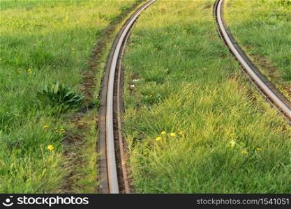 Train rails. Public transportation track covered by lawn. Modern electric vehicle path photography. Classic tram steel way. Industrial urban transport infrastructure. Curve surface of tramway railway