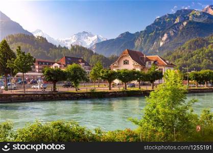 Train station and Aare river in Interlaken, important tourist center in Bernese Highlands, Switzerland. The Jungfrau is visible in background. Old City of Interlaken, Switzerland