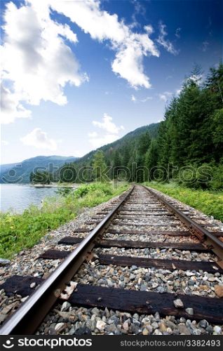 Train tracks near a large lage going through the mountains