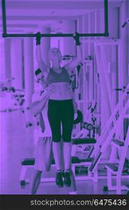 trainer support young woman while lifting on bar in fitness gym indoors duo tone. trainer support young woman while lifting on bar in fitness gym