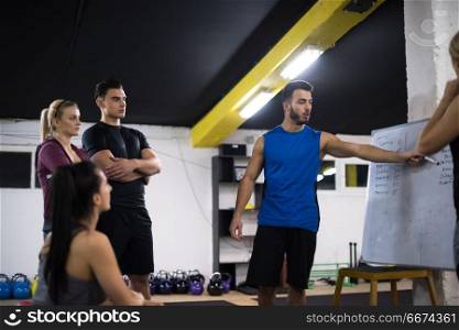 Training course.group of young athletes getting instructions from trainer before exercise at cross fitness gym. athletes getting instructions from trainer