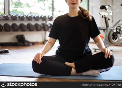 Training gym concept a female teenager sitting on the mat doing preparing herself before doing workout in the gym.